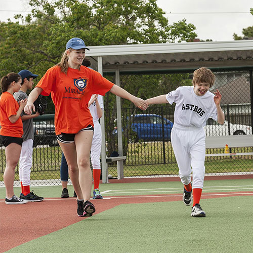 A child in baseball player outfit and a young adult walking on a field.