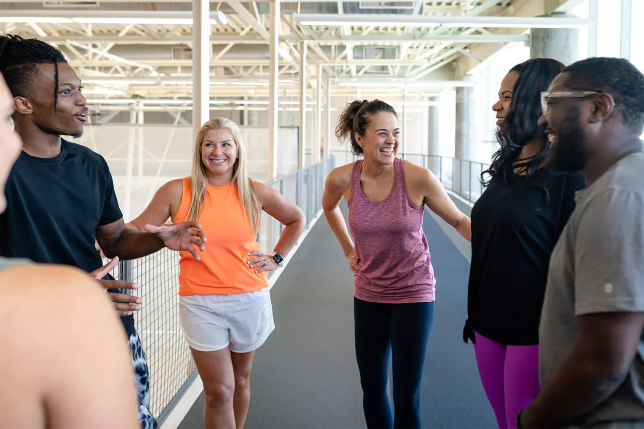 Young adults talk and smile together on the indoor walking track in Houston YMCA