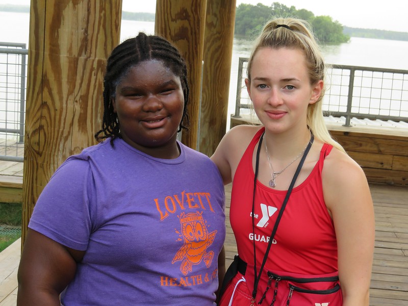 A young girl stands next to a YMCA lifeguard