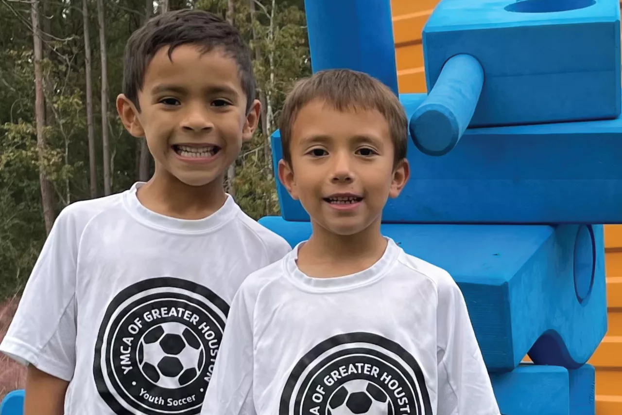 Two children wearing white t-shirts with a soccer ball logo.