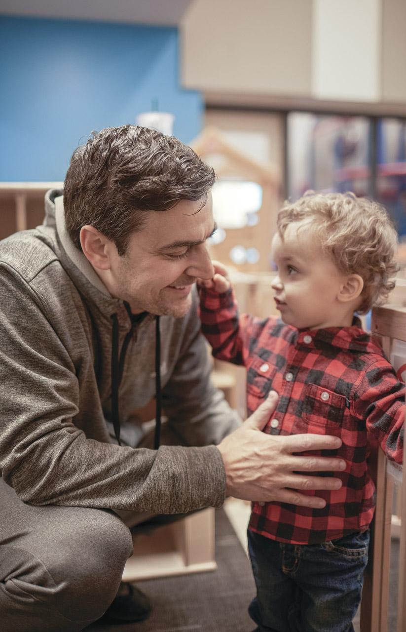 a dad crouches with his toddler