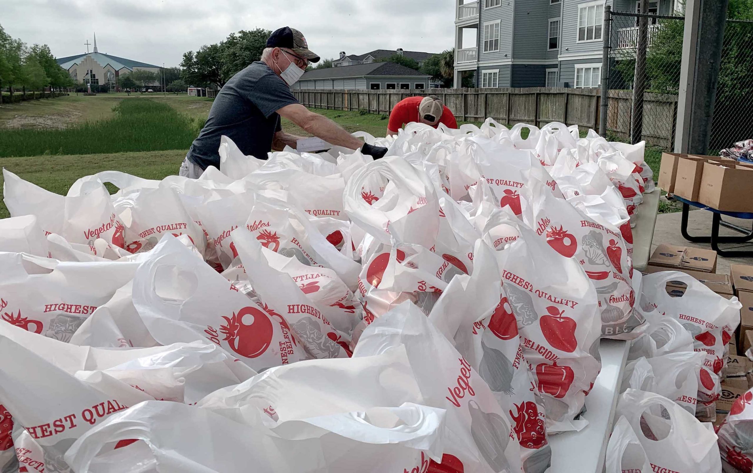 A man gets several hundred grocery bags of food ready for distribution to the community