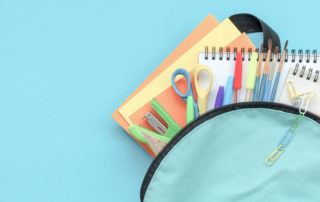 Concept back to school. Full blue School Backpack with supplies on blue background. Flat lay.