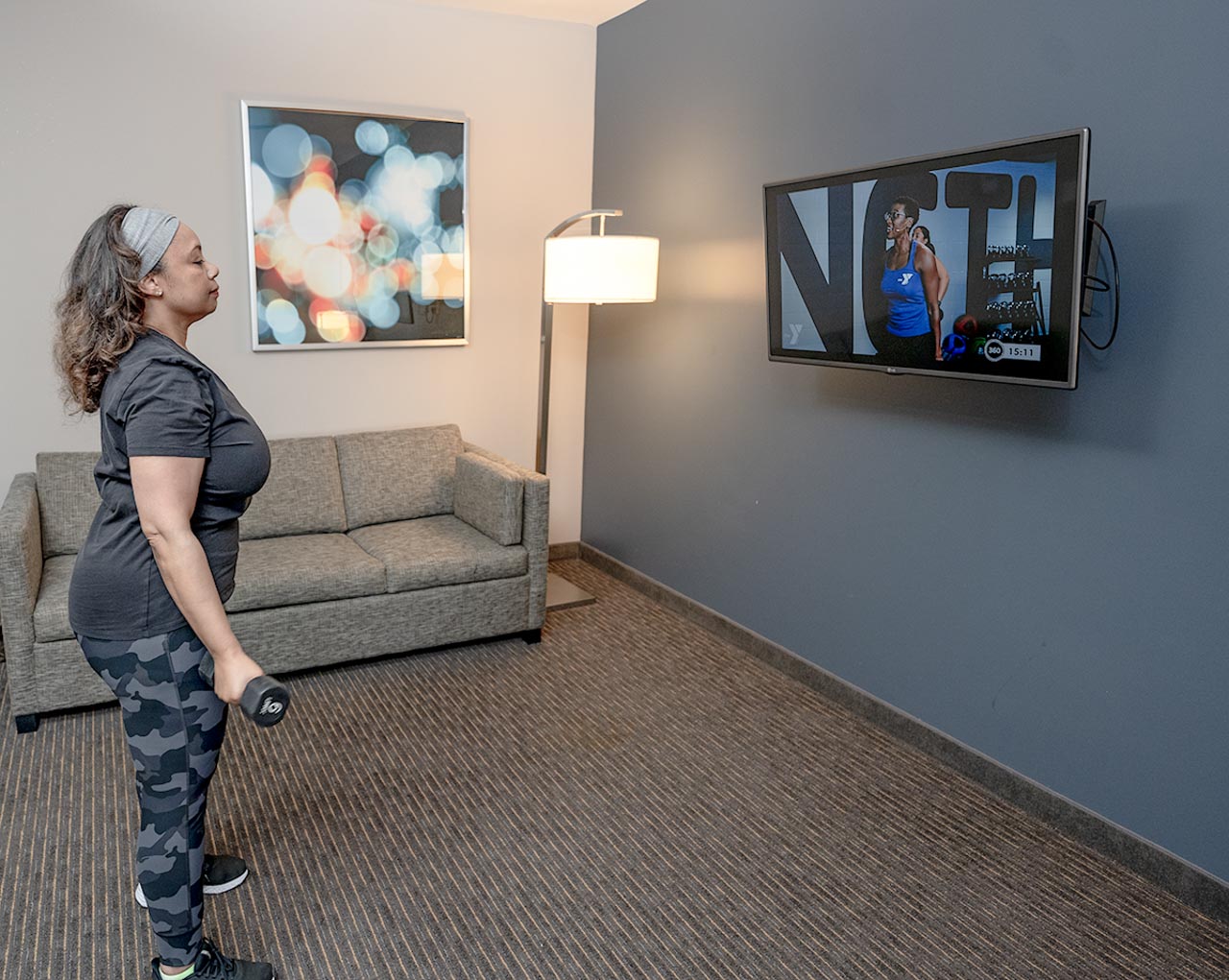 woman lifting weights while watching exercise class remotely