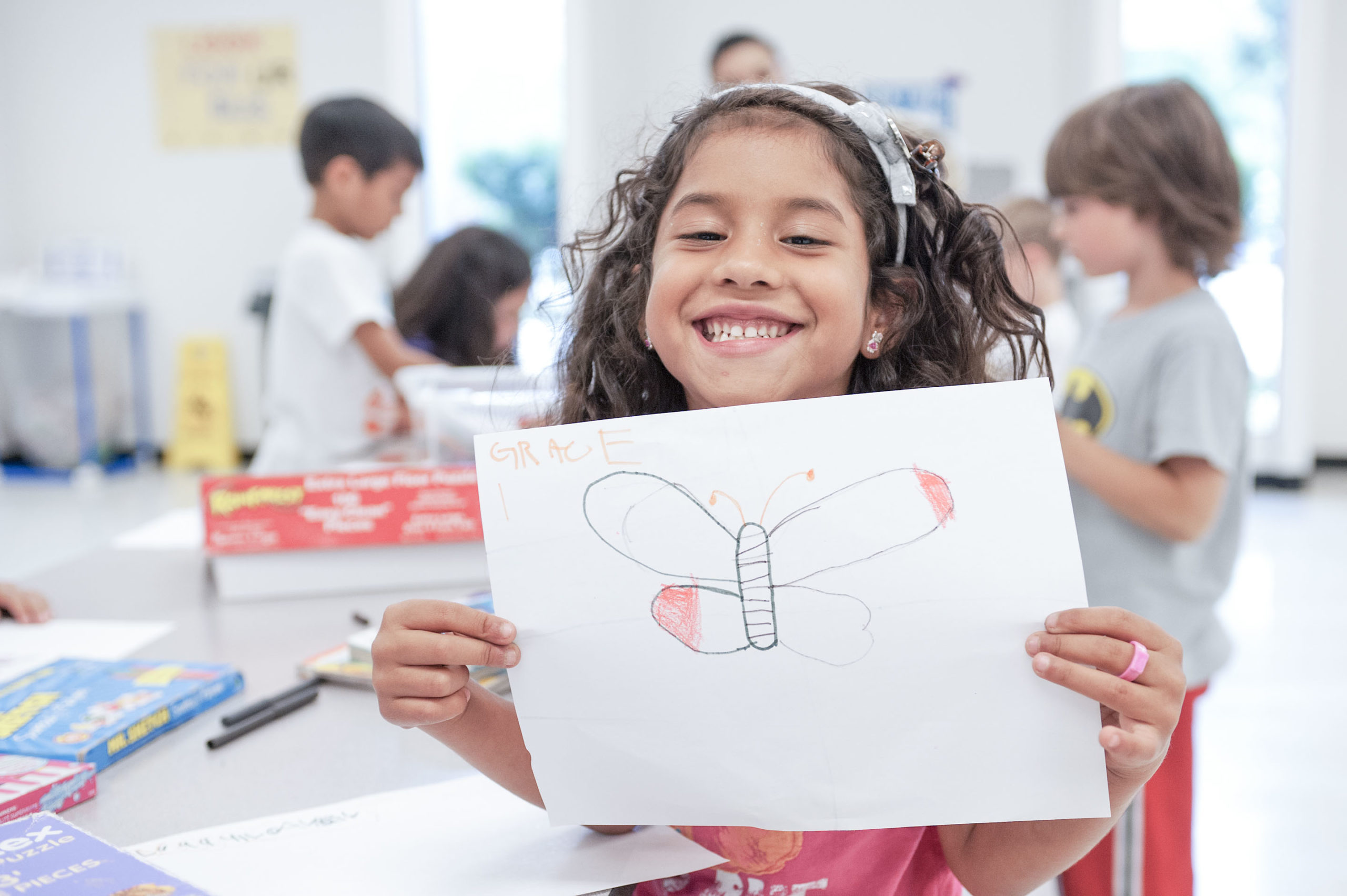 ymca-houston-join-other-advocate-for-the-y-header Smiling young girl holds up a drawing of a butterfly she has created