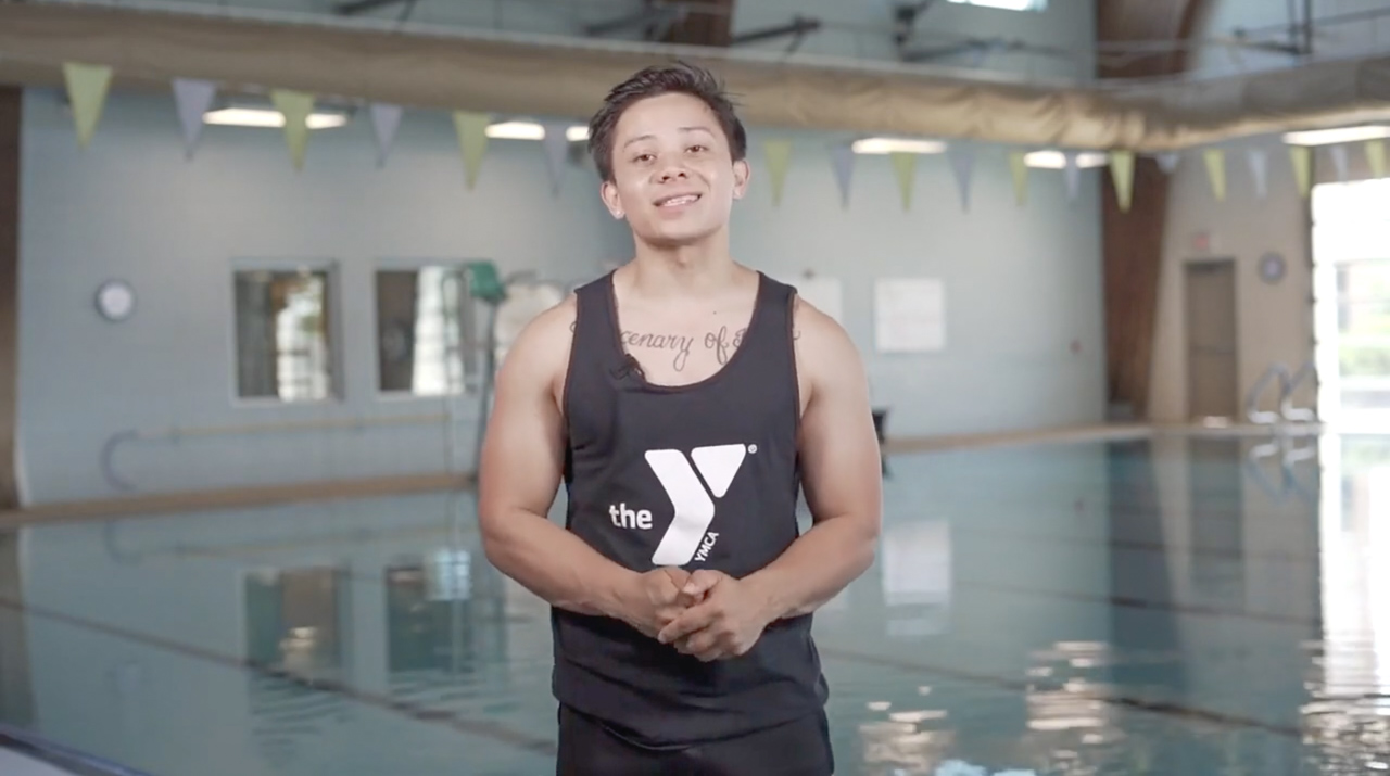 young adult male standing in front of an indoor pool
