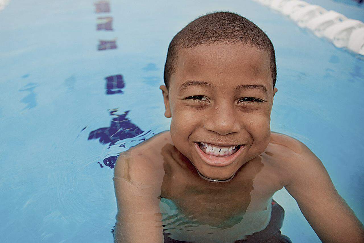 Closeup of a young African American boy smiling in an indoor pool