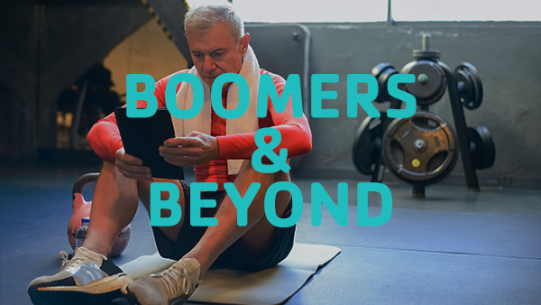 A photo of a person sitting on a gym mat with weights in the background and the text “Boomers & Beyond” overlaid on the image.