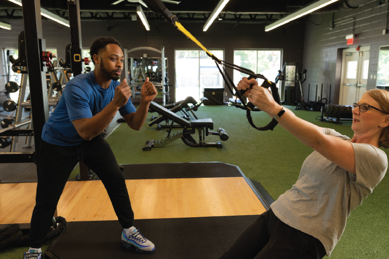 Two people exercising in a gym using TRX straps