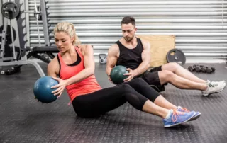 Fit couple doing abdominal exercise with a medicine ball