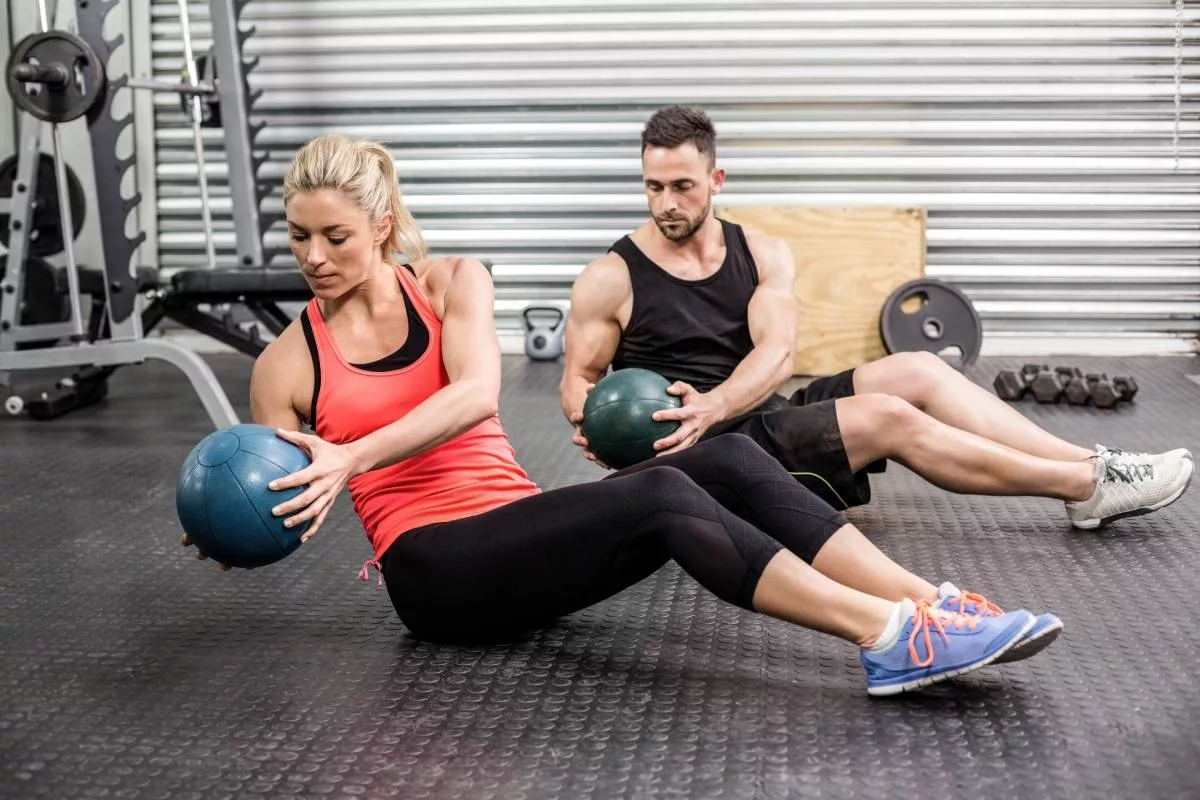 Fit couple doing abdominal exercise with a medicine ball